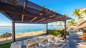 A beachside lounge with sun loungers, a pergola, and a view of the ocean. - Vista Vallarta All Suites on the Beach (Bucerías)