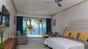 A bedroom with a bed, a sofa, a chair, a wooden side table, and a view of the ocean. - Vista Vallarta All Suites on the Beach (Bucerías)