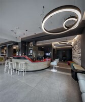 Una hall moderna con una reception a forma di arco, un'area bar e posti a sedere.