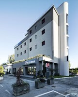 Et moderne hotel med en flad facade, mange vinduer og et skilt med teksten "HOTEL CORSI".