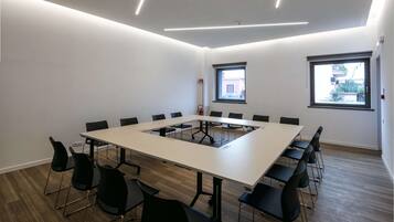 Una sala de conferencias con una larga mesa, sillas negras y dos ventanas.