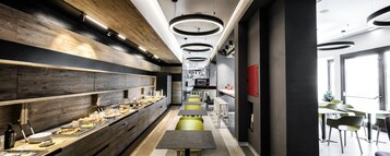 A modern cafeteria with long tables and benches, wooden paneling on the walls, and circular ceiling lights.