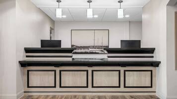 Un'area reception con una panca in legno, un quadro incorniciato di grandi dimensioni e illuminazione a sospensione.