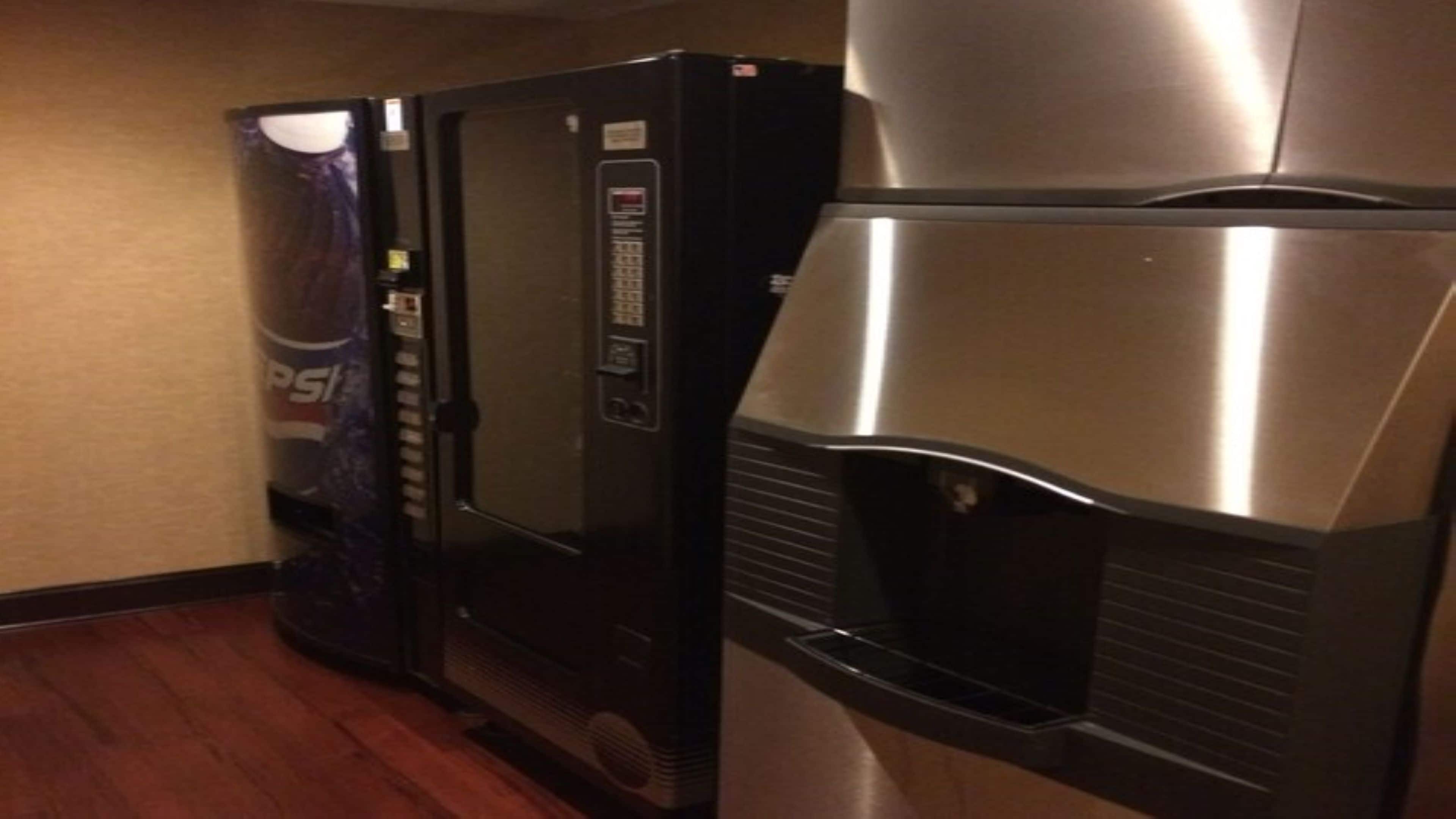 Una máquina expendedora y un refrigerador en un pasillo.