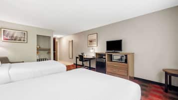 A hotel room with two beds, a desk with a computer, a television, and a microwave.