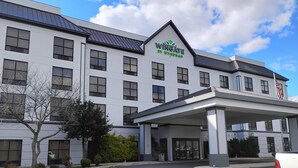 A modern hotel with a prominent 'Wingate by Wyndham' sign, a covered entrance, and a flag. - Wingate by Wyndham North East (North East)