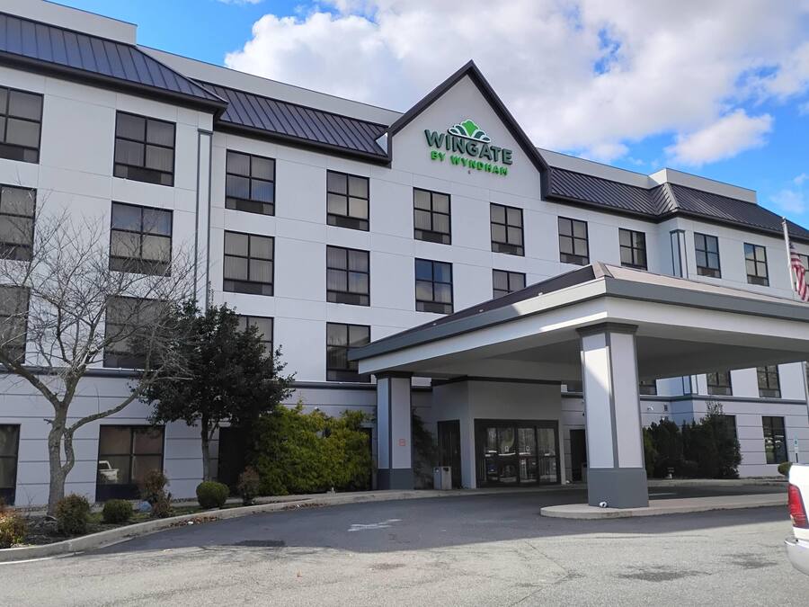 A modern hotel with a prominent 'Wingate by Wyndham' sign, a covered entrance, and a flag.