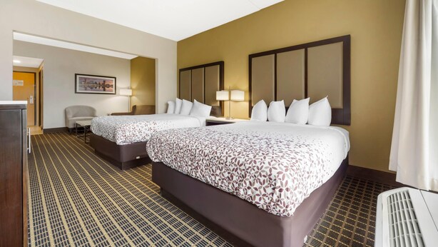 A hotel room with two beds, a desk, a chair, and a wall-mounted TV. - Wingate by Wyndham North East (North East)