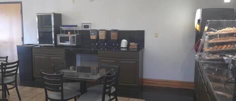 Un restaurante con mostrador, sillas, una mesa y un microondas.