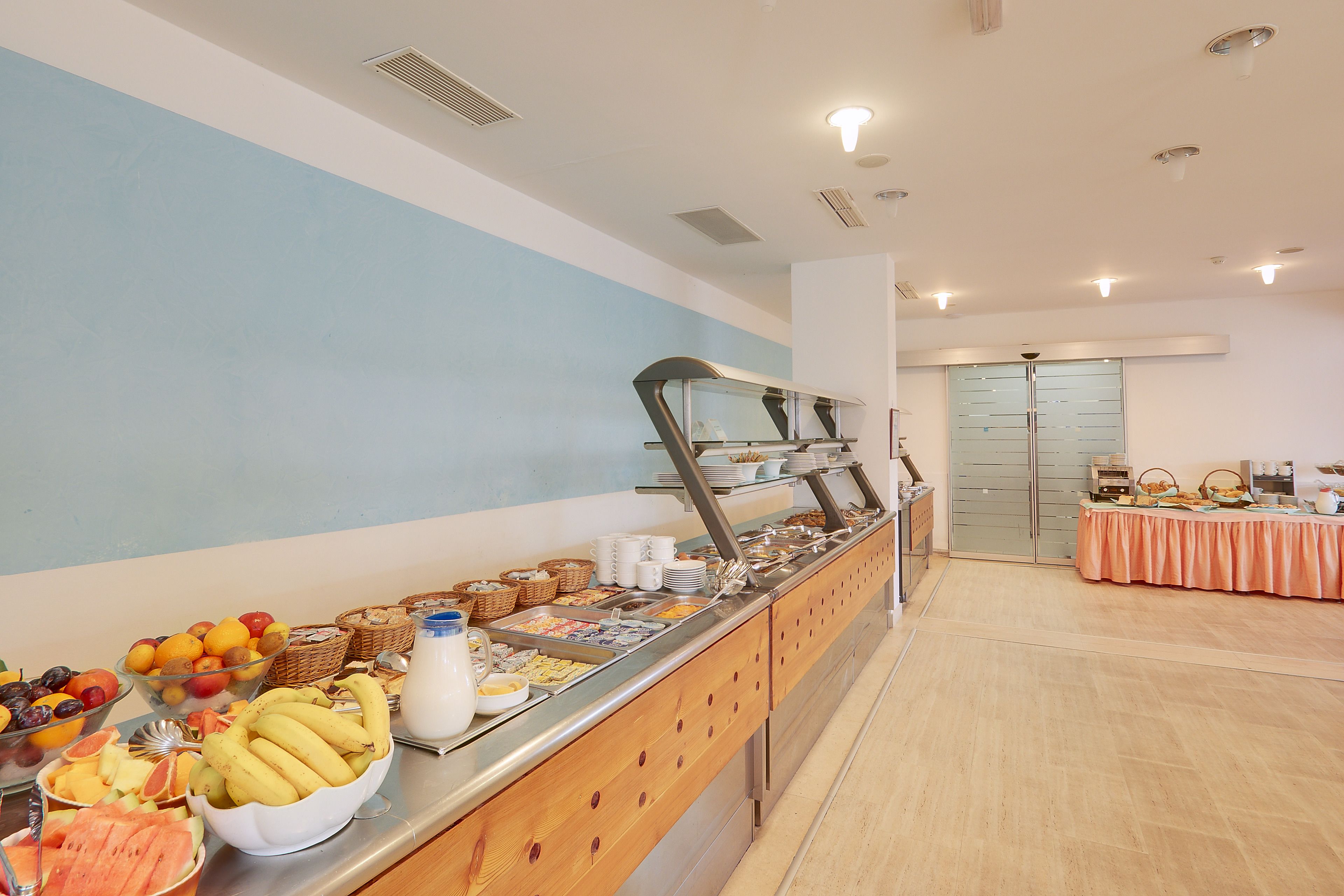 A buffet with various food items and a table with a peach-colored tablecloth.