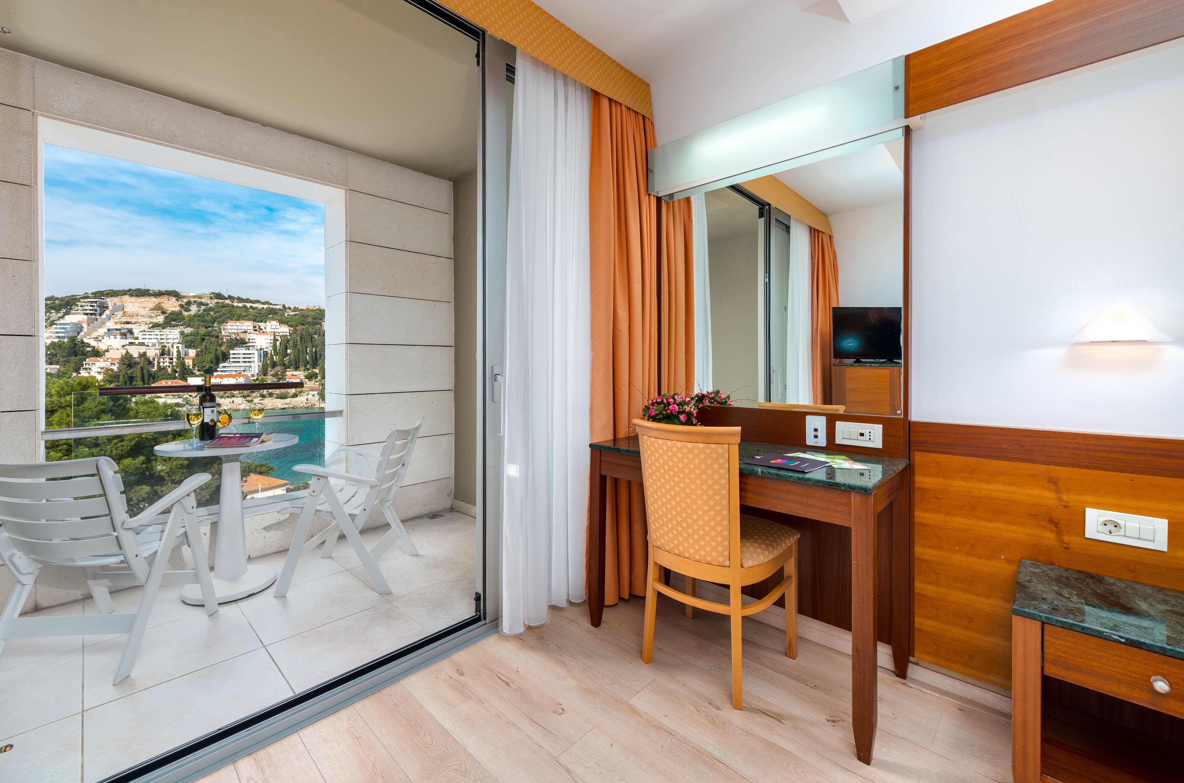 A balcony with a table, chairs, and a view of a cityscape.