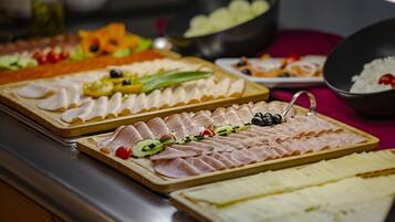 Buffet com diversos alimentos, incluindo carnes, queijos e frutas.