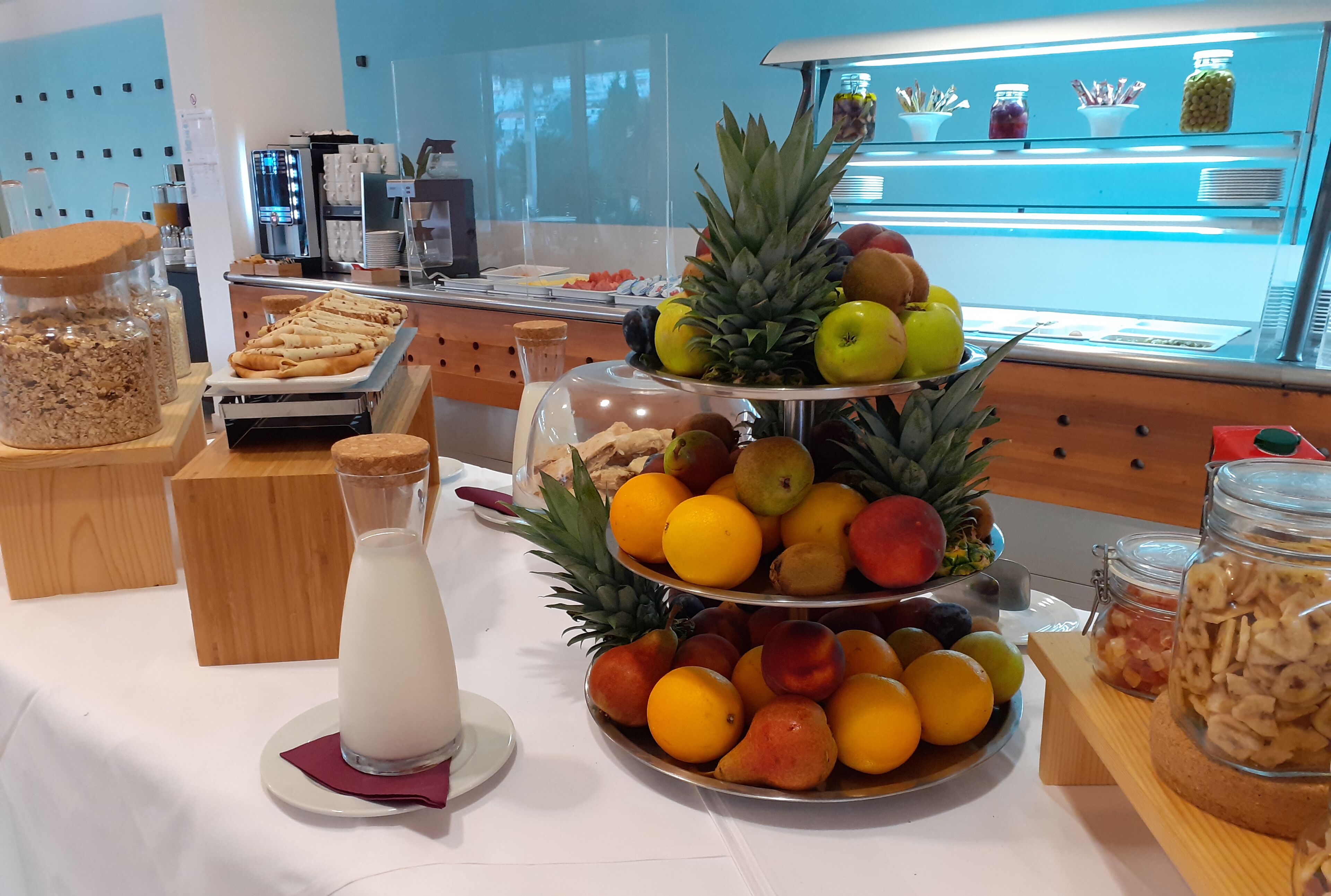 A breakfast buffet with various fruits, pastries, and a milk jug.
