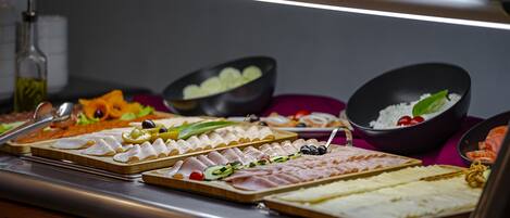 Un bufé con diversos alimentos, incluyendo carnes, quesos y vegetales.