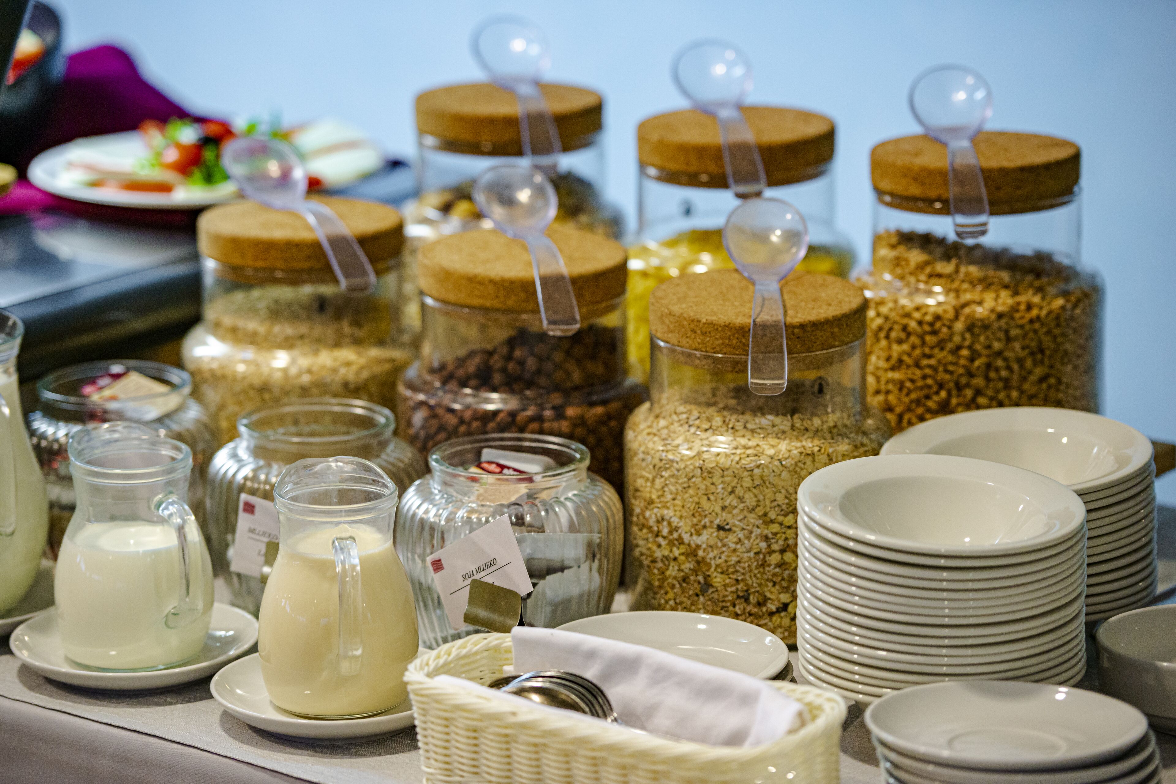 A buffet setup with various food items in jars and plates.