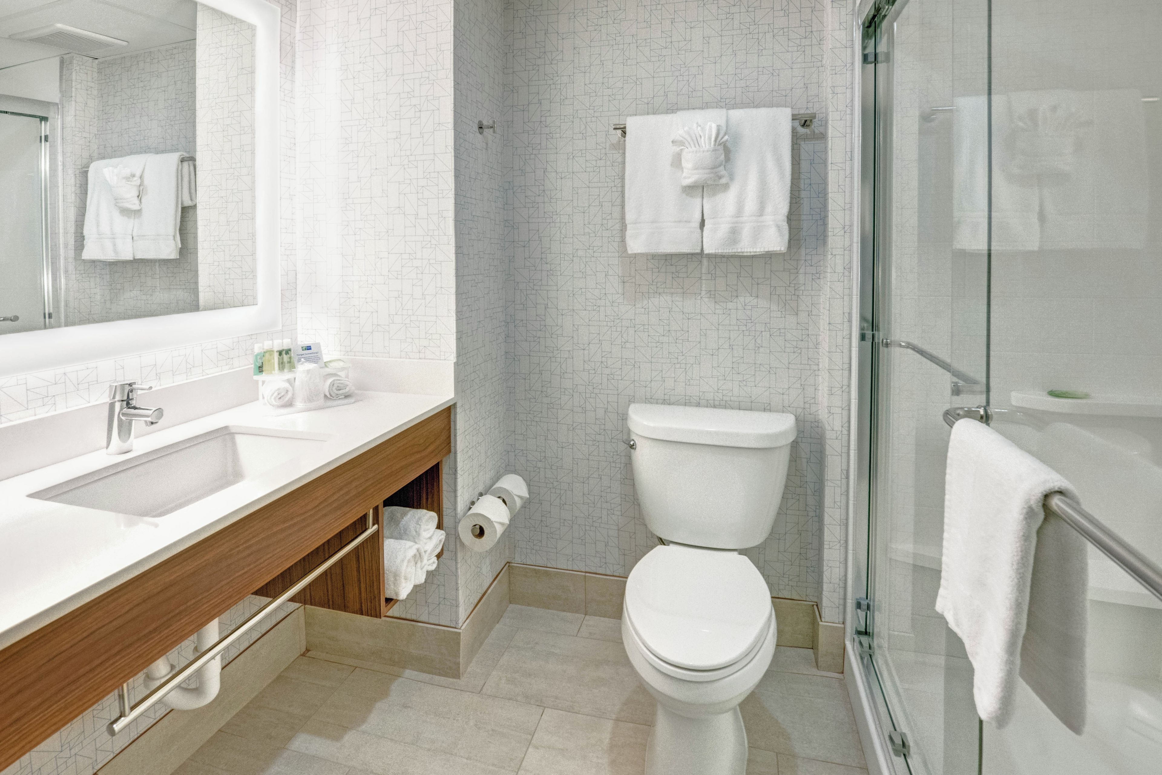 Un baño moderno con lavamanos, inodoro y cabina de ducha de vidrio.