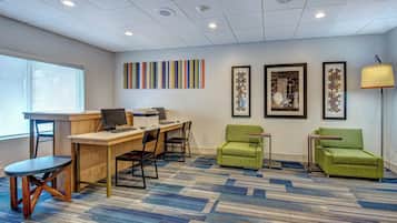 A modern office space with a desk, chairs, a computer, and framed artwork on the wall.