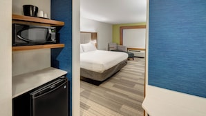 A hotel room with a bed, a microwave, a refrigerator, and a seating area with a chair and a small table. - Holiday Inn Express Woodbridge by IHG (Avenel)