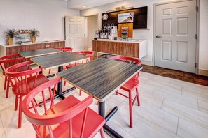 A dining area with red chairs and tables, a kitchen area with a sign reading 'Smart Roast', and a clock on the wall. - Holiday Inn Express Woodbridge by IHG (Avenel)