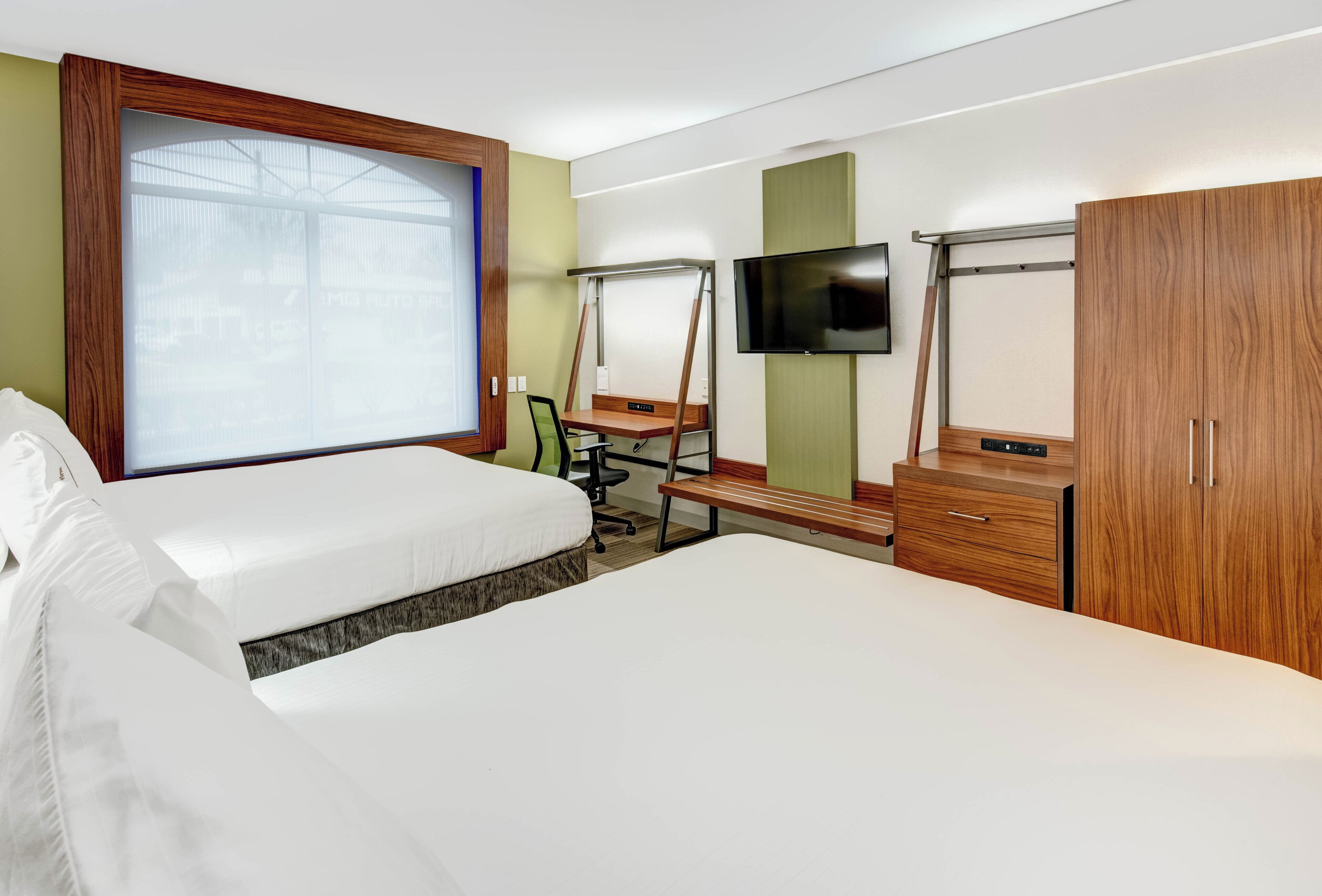A hotel room with two beds, a desk, a television, and a wardrobe.