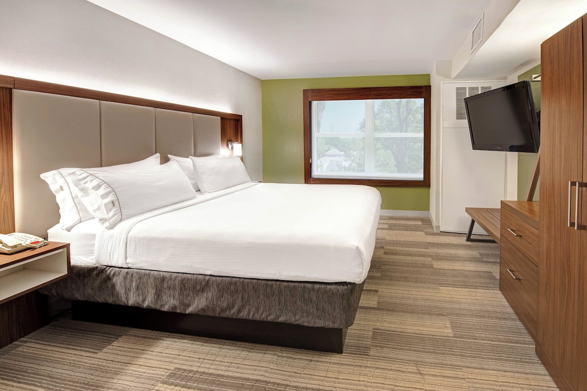 Una habitación de hotel con cama, televisión, escritorio y ventana.