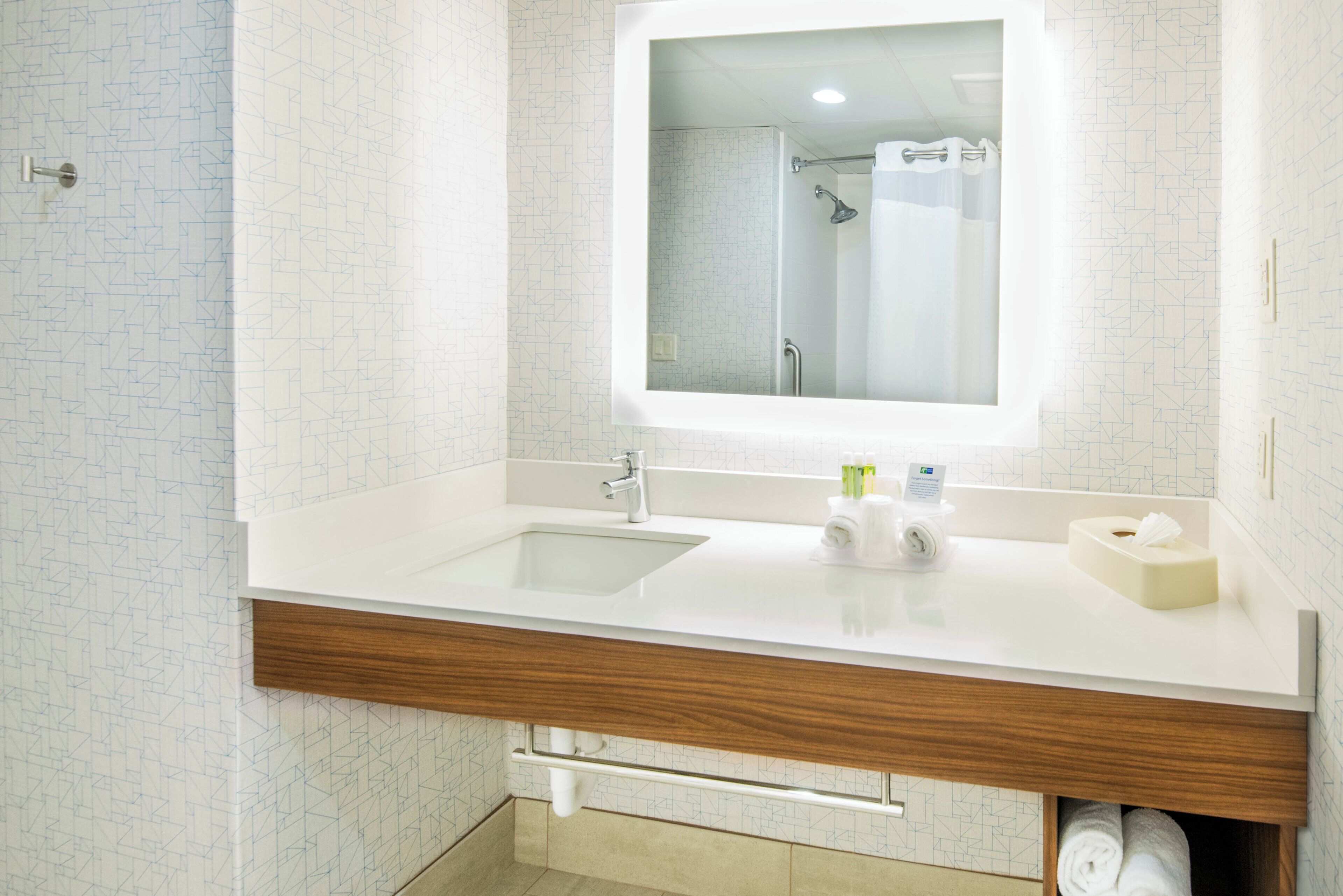 A bathroom with a white sink, mirror, and wooden vanity.