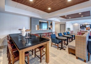 A modern interior with a bar area, seating, and a kitchen in the background.