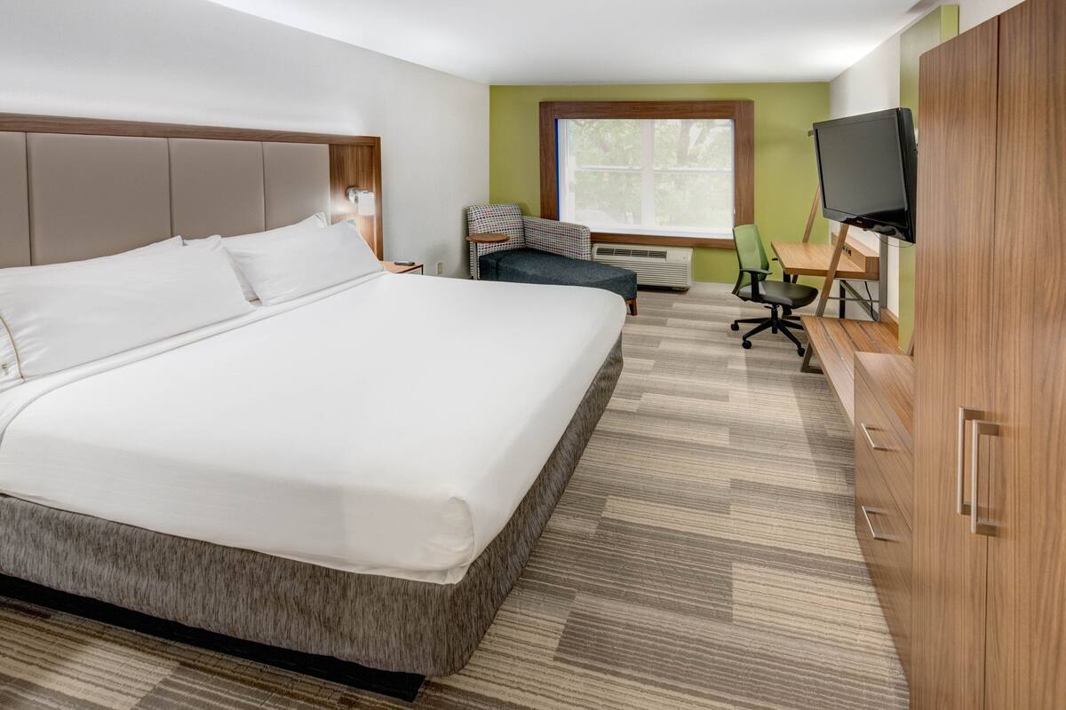 Une chambre d’hôtel avec un grand lit, un bureau équipé d’un ordinateur, une chaise et un téléviseur.