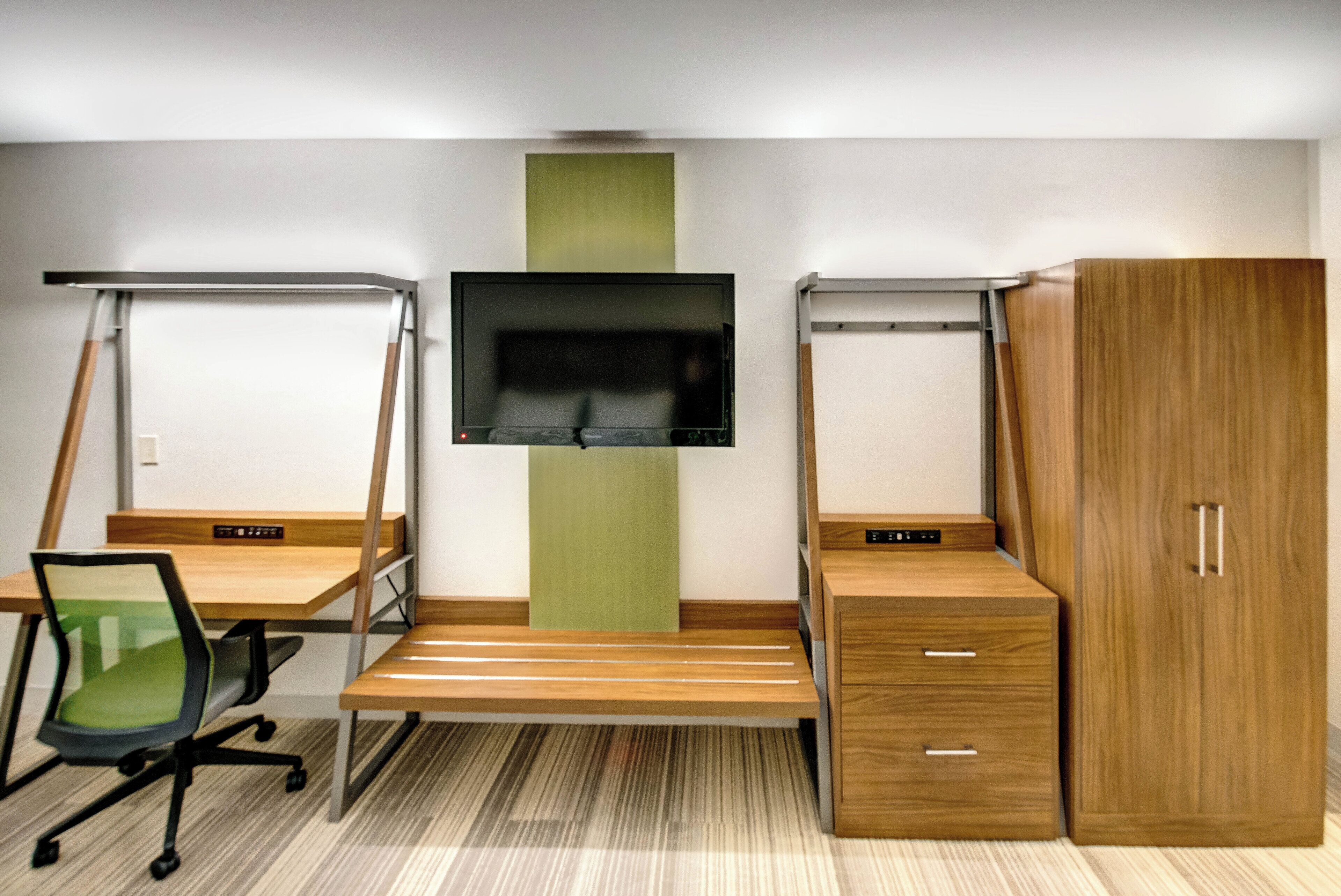 Una habitación con escritorio, silla, televisión y armario.