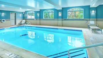 Una piscina con agua cristalina, un trampolín y sillas de descanso.