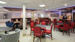 A modern restaurant with multiple seating areas, including round tables and booths, and a coffee station.
