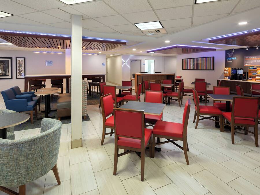 A modern restaurant with multiple seating areas, including round tables and booths, and a coffee station.