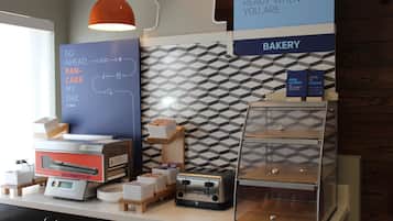 A breakfast area with a sign indicating it's ready when you are, a bakery section, and a waffle maker on the counter.