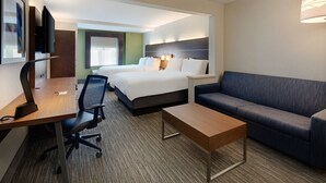 A hotel room with a bed, a sofa, a desk with a chair, a TV, and a lamp.