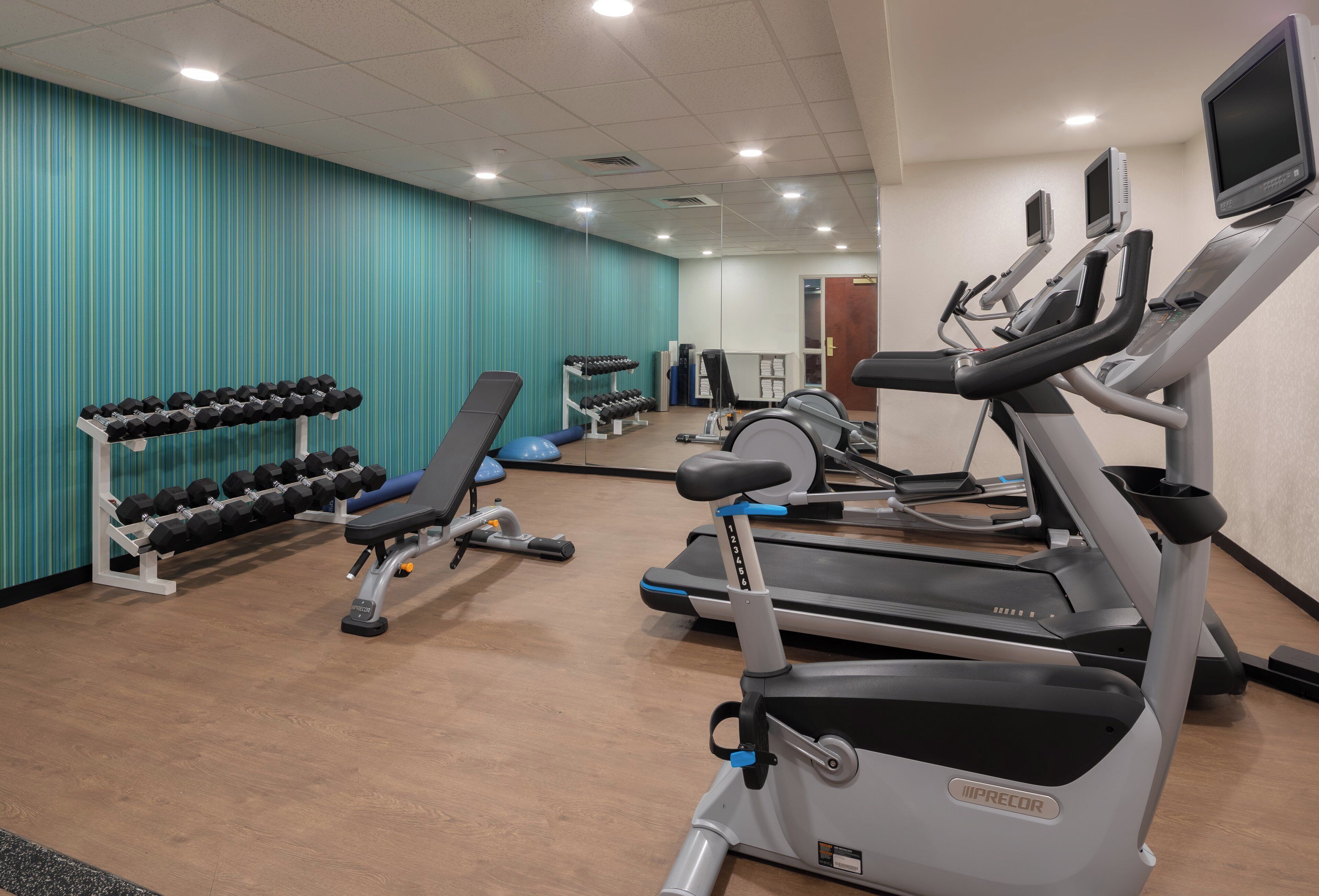 A gym with treadmills, elliptical machines, and weight stations.