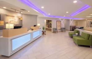 Un espace d’accueil d’hôtel comprenant un comptoir de réception, un coin salon et un buffet.
