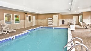 An indoor swimming pool with clear water, a lifeguard chair, and a changing room with a shower.