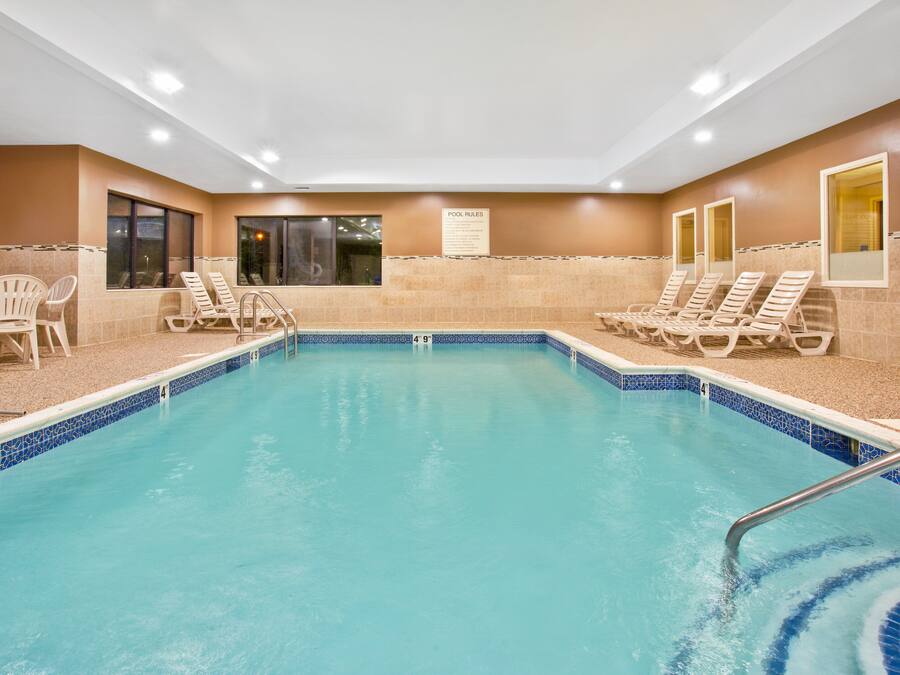 Una piscina interior con sillas de descanso y un cartel con las normas de la piscina.