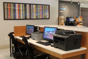 Una recepción con múltiples monitores de computadora, una impresora y una estación de café al fondo.
