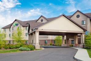 Entrada de un hotel con un camino cubierto, varios pisos y el letrero de Holiday Inn Express.