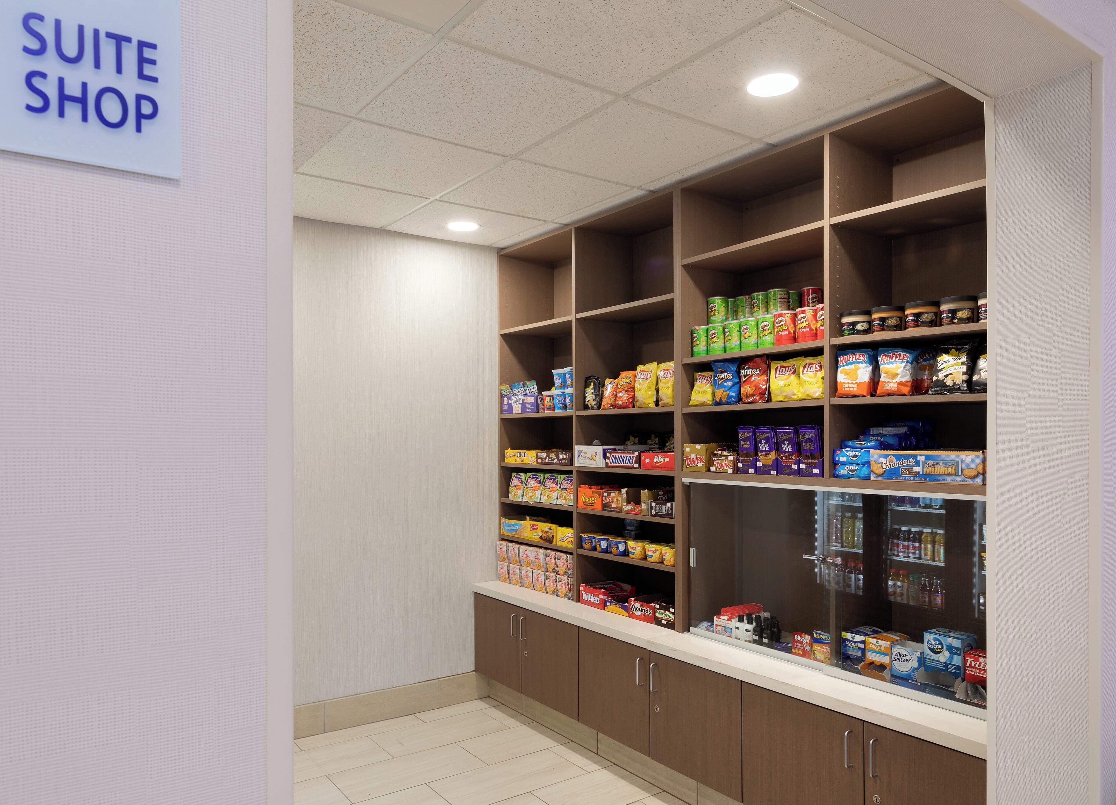A well-organized suite shop with shelves stocked with snacks, beverages, and toiletries.