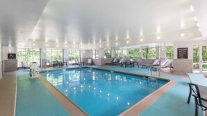 En inomhuspool med klart vatten, omgiven av solstolar och en poollyft.