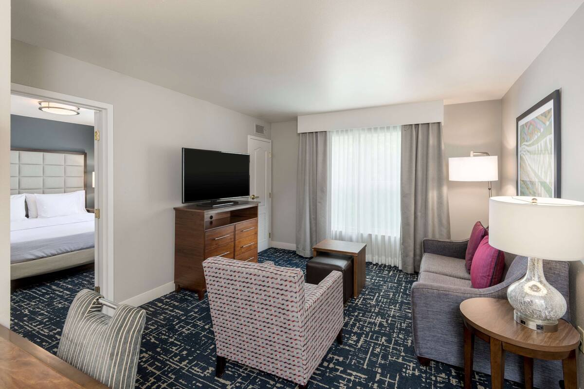Una habitación de hotel con una cama, un televisor, un escritorio, un sofá y una lámpara.