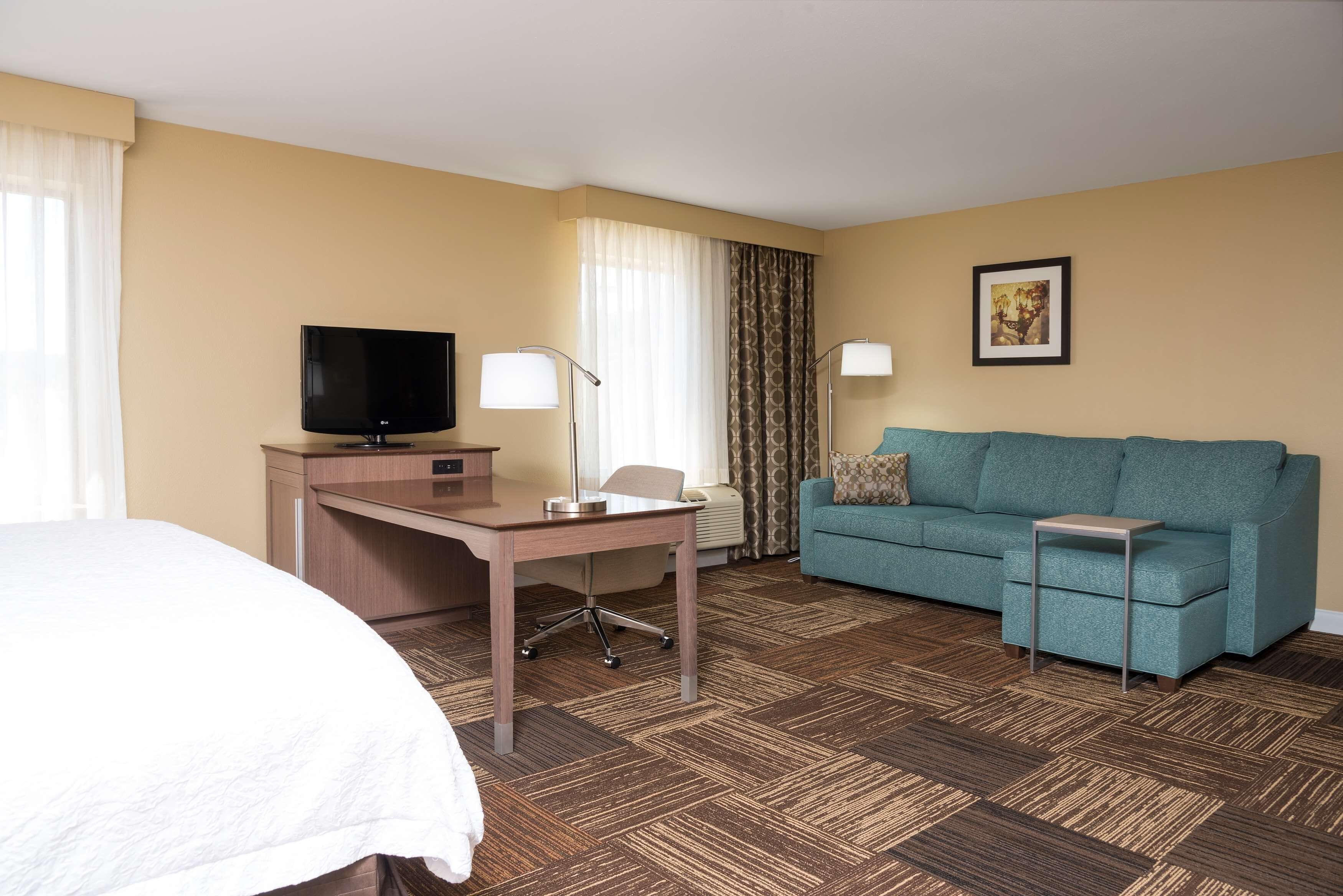 Une chambre d’hôtel comprenant un lit, un bureau avec une télévision, un canapé et une petite table.