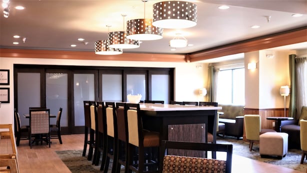 A hotel lobby with a dining area, multiple chairs, a bar, and a sofa. - Hampton Inn & Suites Fremont (Fremont)
