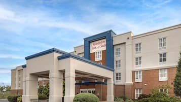 A Hampton Inn & Suites hotel with a covered entrance, brick facade, and a sign above the entrance.