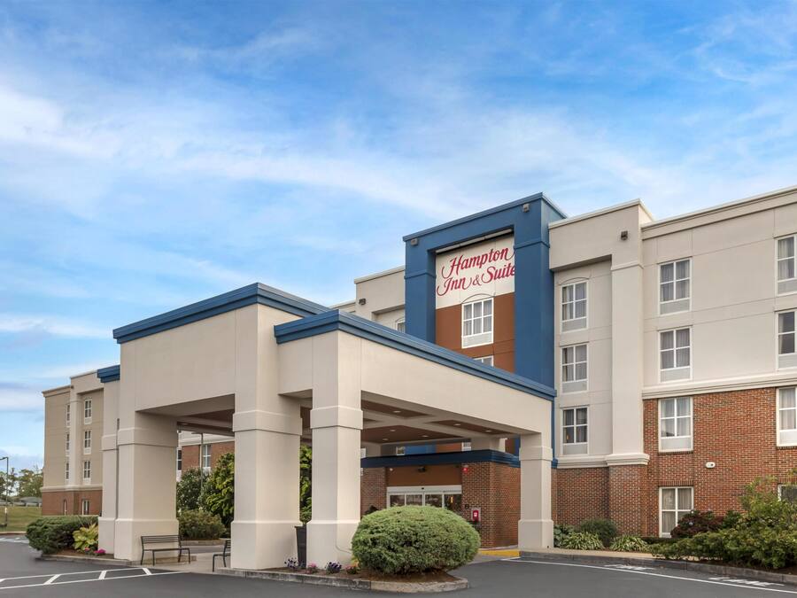 A Hampton Inn & Suites hotel with a covered entrance, brick facade, and a sign above the entrance.