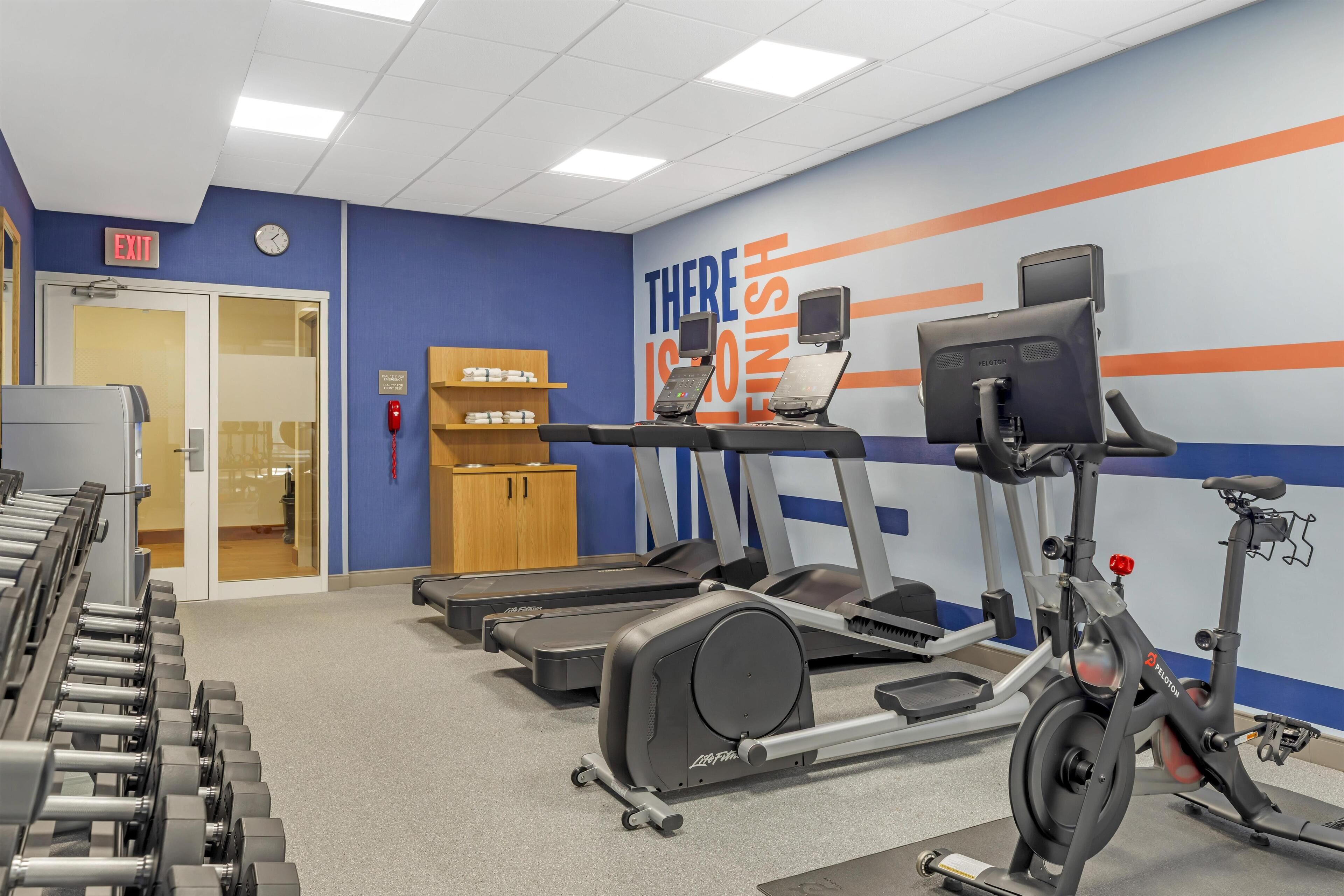 Une salle de sport équipée de tapis de course, de vélos d’appartement et d’haltères.