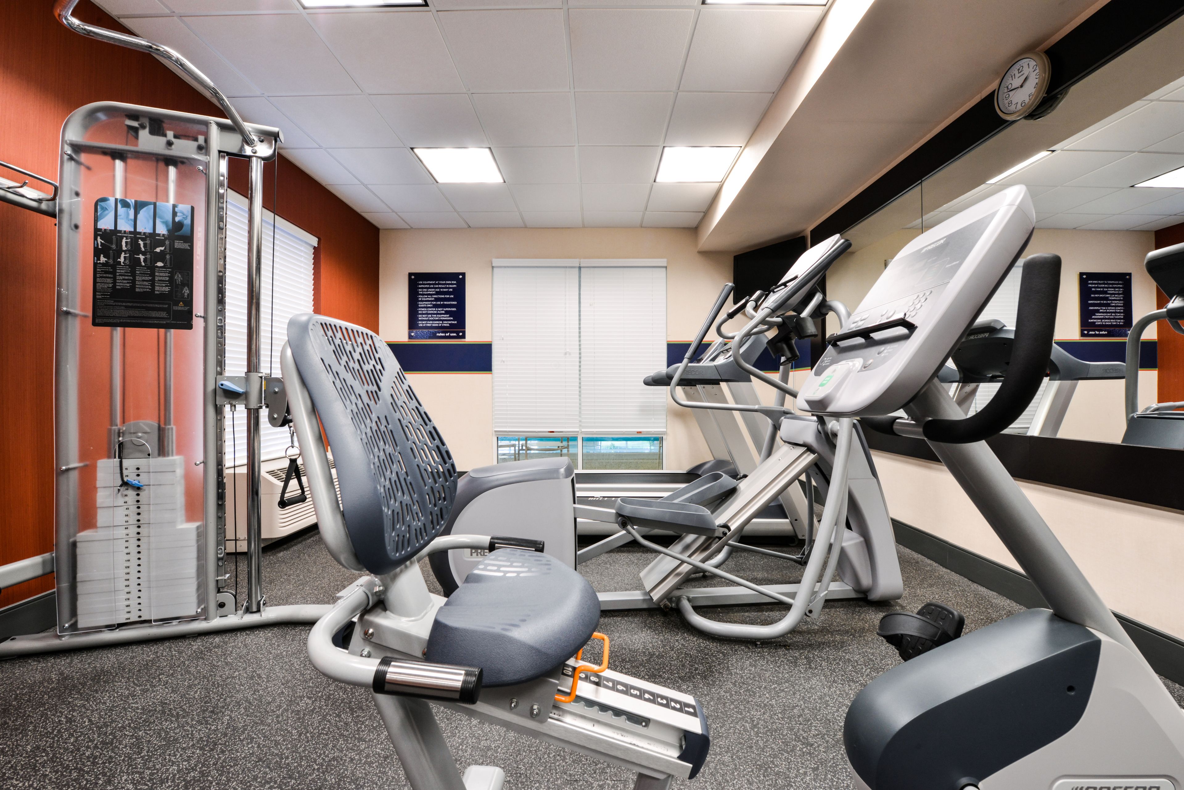Une salle de sport équipée de matériel d’exercice, avec une horloge et des affiches informatives accrochées aux murs.