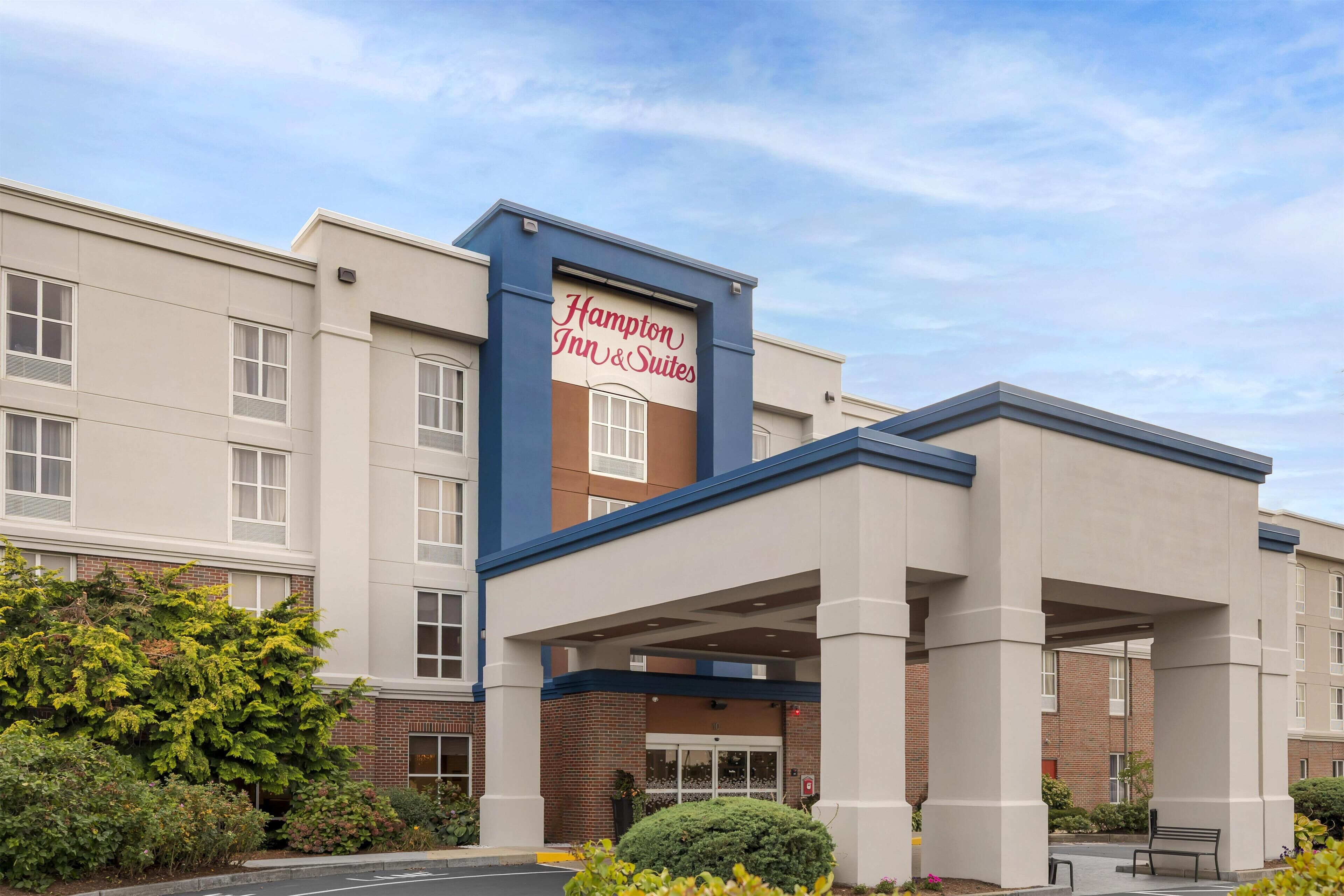A Hampton Inn & Suites building with a clear entrance, a sign, and a covered parking area.